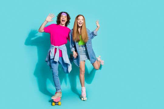 Full body photo of carefree teenagers like sports riding skateboard and rollerskates raised arms up isolated on aquamarine color background