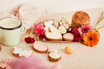 Sweet decorated cookies with milk, Easter cake and flowers. Spring floral cozy aesthetic background.