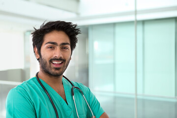 A portrait of an Indian man who works as a doctor or nurse. He is wearing a green Scrubs with a stethoscope around his neck.