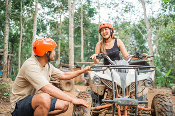 happy asian woman riding the atv while the asian man checking on it before go through the atv tracking arena © Odua Images