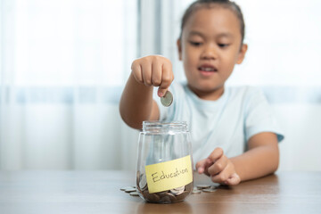 A girl is putting coins into a piggy bank, Savings for education
