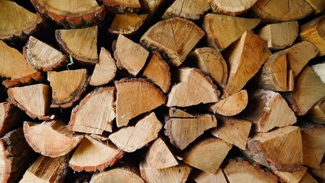 Chopped oak firewood stacked in a woodshed for the winter, close-up. Background of firewood for heating the house, camera movement
