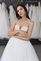 Portrait of a beautiful young bride in a wedding dress and with expensive jewelry in a wedding salon.