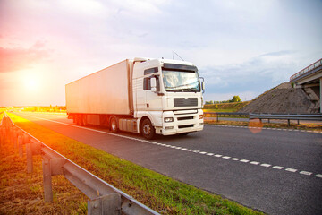 A white modern truck with an isothermal refrigerated semi-trailer transports perishable products in...