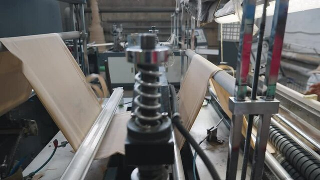 Automated machine processing the fabric used for eco bags manufacturing. Conveyor machine divides the sustainable material for eco bags. Machine producing the eco friendly bags at the facility.