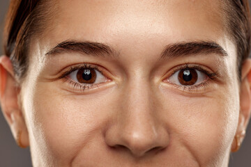 Close-up of female's brown eyes, no makeup looking on camera. Health care, vision. Woman smiling....