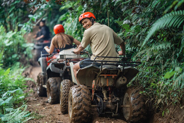 handsome asian man looking back and smiling while riding atv at atv arena with his partner