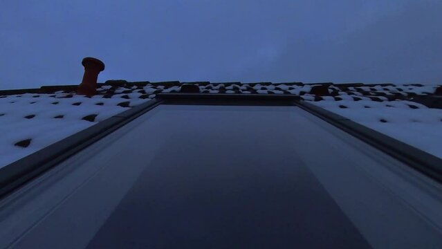Dachfenster in verschneitem Dach mit sich spiegelnden Wolken die Abends im Zeitraffer vorbeiziehen, rote Ziegel, Dachd&auml;mmung