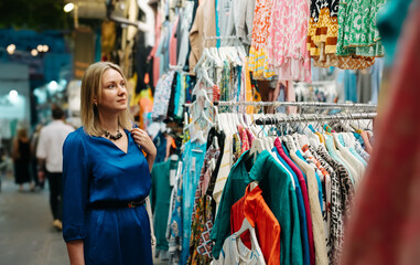 Fototapeta na wymiar Woman choosing a clothes at the evening bazaar.