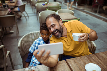 Father and son taking a selfie at a cafe terrace