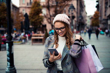 Young stylish woman using smartphone while shopping in city