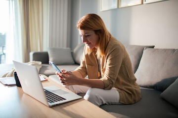 Concerned woman holding bill using laptop at home