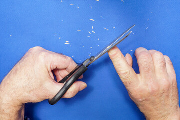 The man cuts his own nails with large scissors.