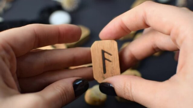 Wooden runes in hand on black table background. Scandinavian magical esoteric symbols and signs for divination and prediction of the future and destiny, esotericism concept.