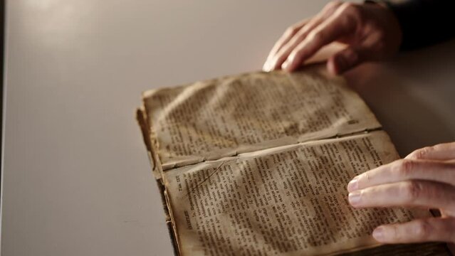 Close-Up of a Persons Hands Opening and Turning the Pages of an Old Book. Man read Holy Bible