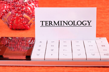 TERMINOLOGY text written on a white business card on a calculator on an orange background