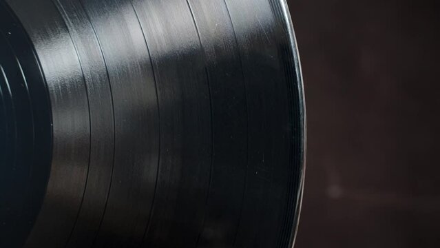 Close-up of a vinyl record on a black background. It spins, revealing its texture.