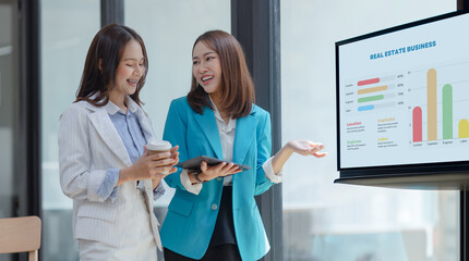 Happy two asian businesswoman working with tablet in meeting room, Businesswoman standing and talking about ideas in office workplace.