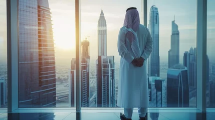 Foto op Plexiglas Successful Muslim Businessman in Traditional White Kandura Standing in His Modern Office Looking out of the Window on Big City with Skyscrapers. Successful Saudi, Emirati, Arab Businessman Concept. © Hope
