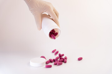 Hand with surgical glove dropping all the vitamins from a bottle without control on the floor