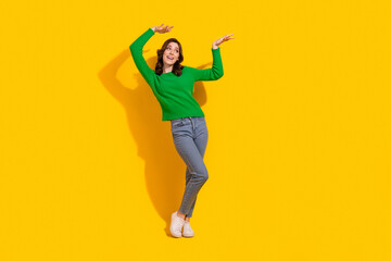 Full body length photo of funky girl raised palms up looking empty space dancing weekend party isolated on yellow color background