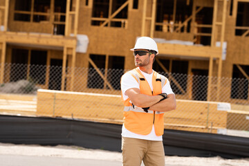 roofer builder working on roog structure of building on construction site. handsome young male builder in hard hat smiling at camera. Construction Worker on Duty. Contractor and the Wooden House Frame