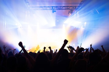 Crowd cheering and watching a band on stage, blurred motion, shallow DOF.