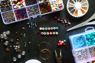 Colorful beads and various jewelry making supplies on dark background. Letter beads spelling...