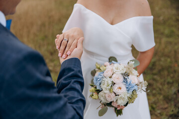 Close-up photo of a woman's hand with a wedding ring in the hands of her beloved man