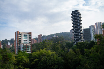 Fototapeta premium amazing wide shot of nature landscape with buildings popping out from behind the greenery during a bright cloudy day