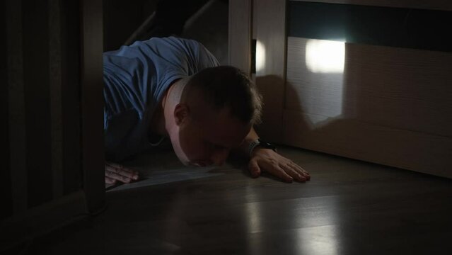 A sick or injured man crawls on the floor in an apartment