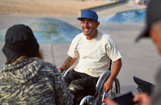 portrait man with disability in wheelchair with friends at skatepark