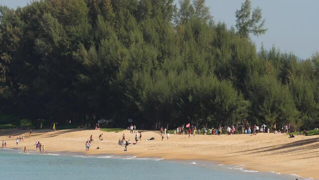 People on the coast of Mai Khao, Phuket. Person looking at the flying plane above the sea, travel and active lifestyle concept