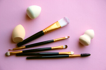 makeup brushes and sponges on a pink background