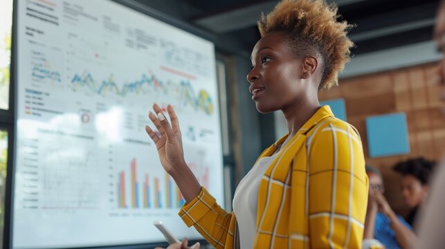 Big data analysis and fintech e-commerce concept with African American woman as executive director presenting growth statistics to diverse conference meeting members in the office with graphs