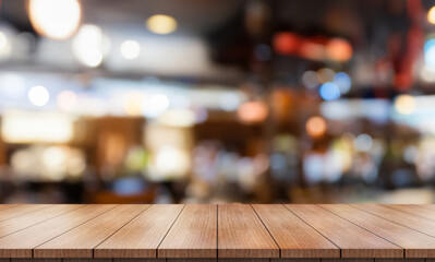 Empty wooden table top with lights bokeh on blur restaurant background.