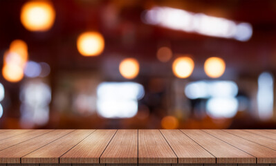 Empty wooden table top with lights bokeh on blur restaurant background.