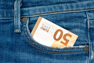 Folded 50 Euro banknote in front pocket of blue jeans