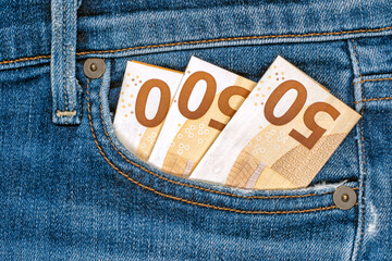 Three folded 50 euro bills in front pocket of blue jeans