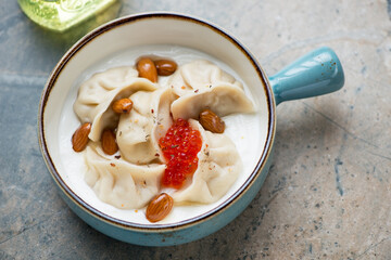 Vareniki or dumplings with yogurt and red caviar in a turquoise serving pan, horizontal shot on a...