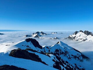 Snow covered mountains peaking out over clouds