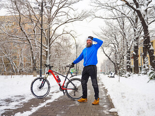 Smiling bearded man with a bicycle in a winter park