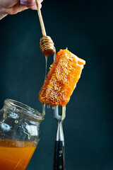 A honey stick with honey in a woman's hands watering the honeycombs. Honey and beekeeping products.