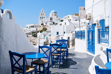 Typical street with blue tables and chairs among white houses on the Greek island of Santorini, Pyrgos village. Greek Islands, European Vacation. Travel, holidays, relax, adventure.