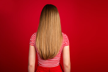 Photo of attractive slender girl wear striped top standing back showing long hair isolated red color background