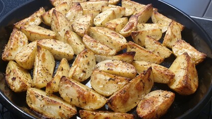 Roasted potatoes with herbs in a black tray.