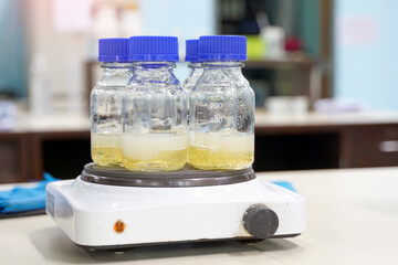A glass bottle contains aloe vera gel that has been heated with a hot plate in a chemistry laboratory to be used as an ingredient in aloe vera skin care lotion. Soft and selective focus.