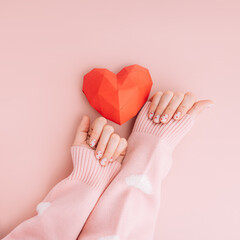 Manicure for Valentine's Day with a red heart on a pink background.
