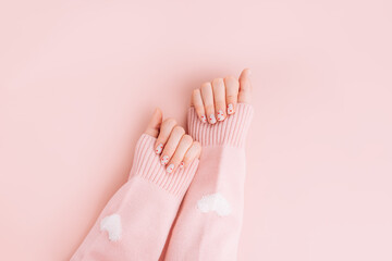 Manicure for Valentine's Day is white with red hearts on pink background.