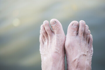 As for the body, the feet of an elderly person on the background of water.